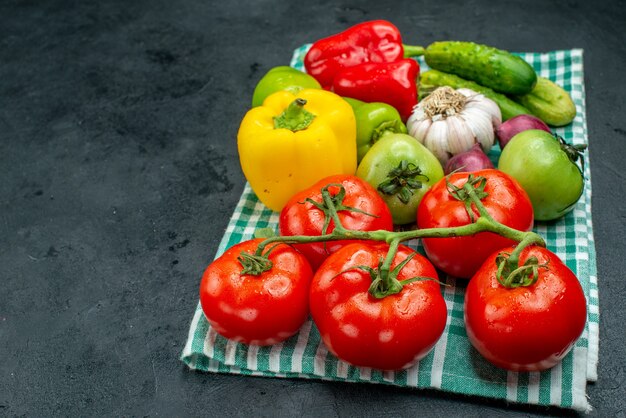 바닥 보기 야채 마늘 오이 토마토 가지 녹색 토마토 피망은 여유 공간이 있는 검은 테이블에 있는 녹색 식탁보에 있습니다.