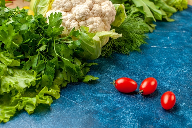 Bottom view vegetables parsley dill lettuce cauliflower cherry tomatoes on blue table