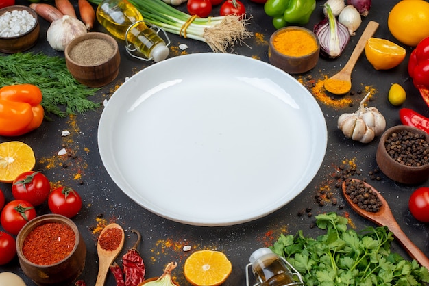 Free photo bottom view white round plate black pepper in small bowl oil bottle coriander garlic dill green onion on table