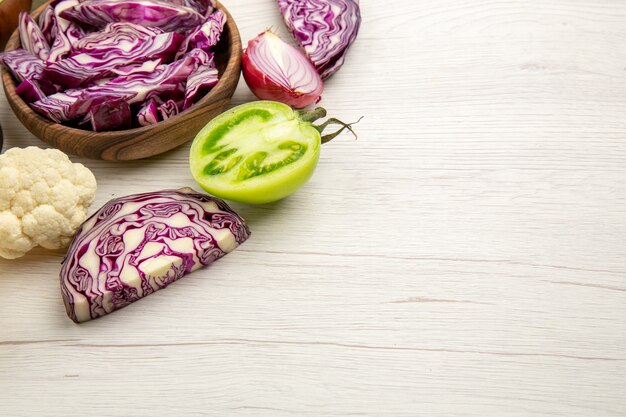 Foto gratuita vista dal basso ciotole di legno con verdure tagliate cavolfiore cipolla cavolo rosso pomodoro verde su tavolo di legno bianco con spazio libero