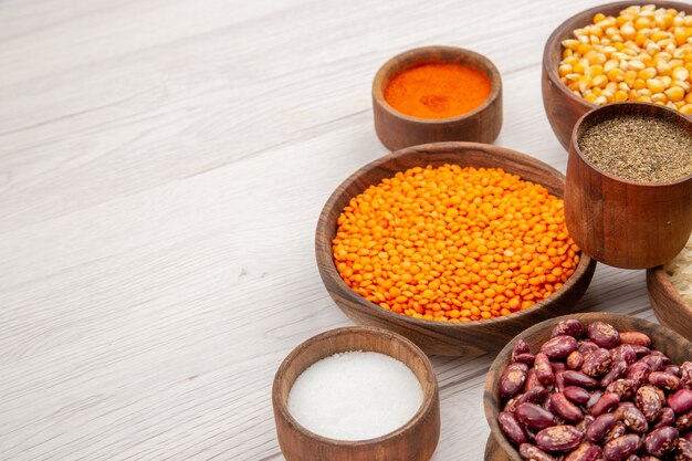 Bottom view wooden bowls with lentiles corn seeds pumpkin seeds beans different spices on grey table free space