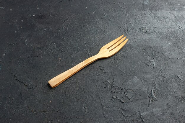Bottom view wooden fork on dark table with free space