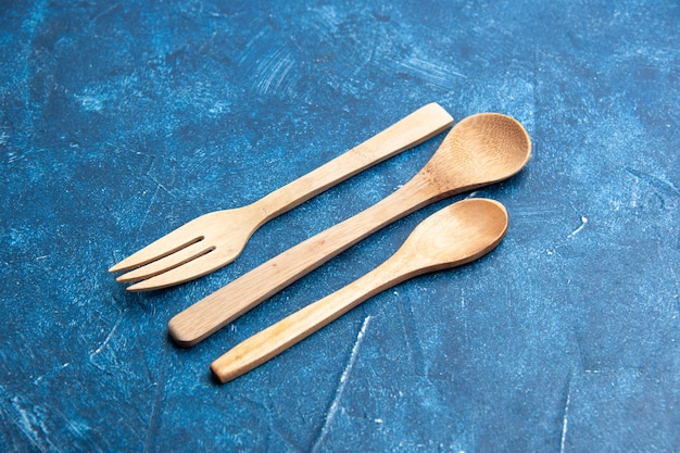 Bottom view wooden fork spoon knife on blue surface free space