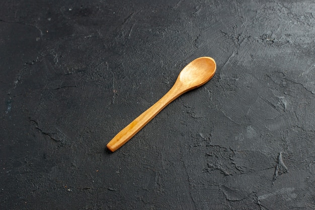 Free photo bottom view wooden spoon on dark table free space