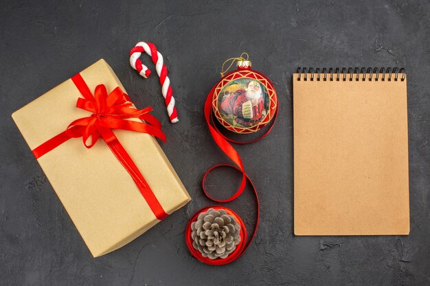 Bottom view xmas gifts in brown paper ribbon xmas tree toy on newspaper on dark background