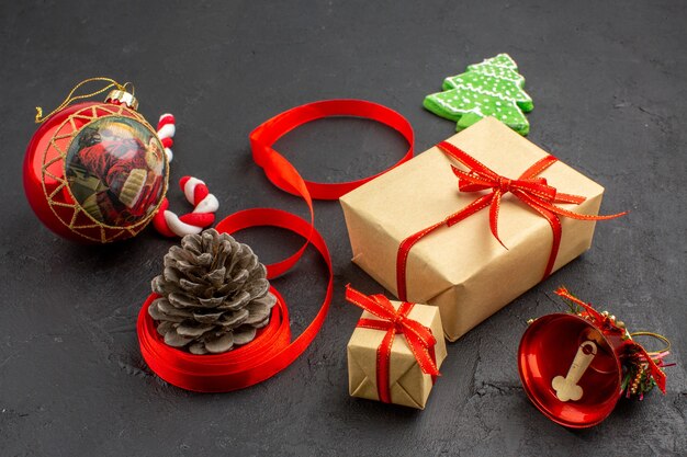 Bottom view xmas gifts in brown paper ribbon xmas tree toy on newspaper on dark background