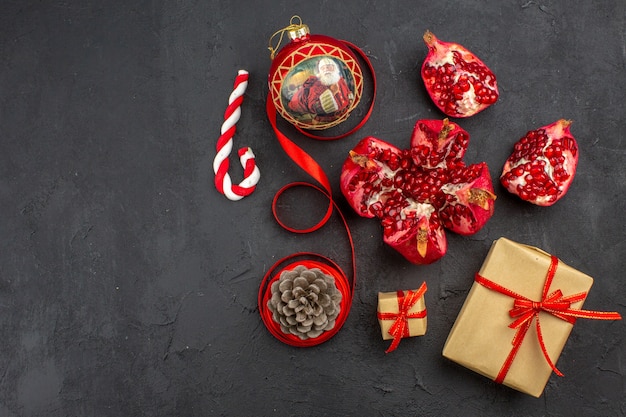 Bottom view xmas gifts in brown paper ribbon xmas tree toy on newspaper on dark background