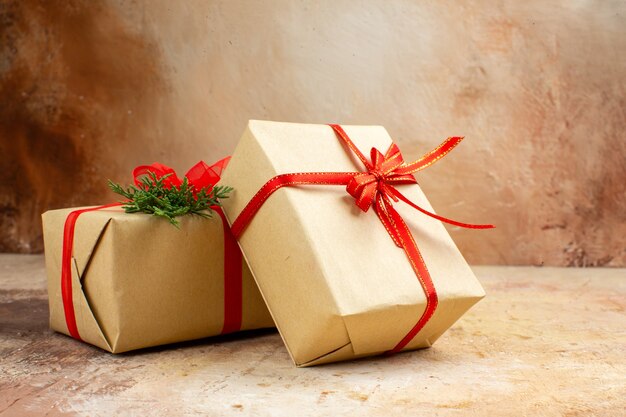 Bottom view xmas gifts in brown paper ribbon xmas tree toy on newspaper on dark background