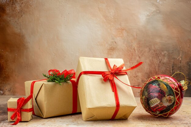 Bottom view xmas gifts in brown paper ribbon xmas tree toy on newspaper on dark background