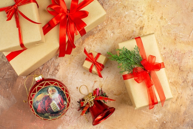 Bottom view xmas gifts in brown paper ribbon xmas tree toy on newspaper on dark background