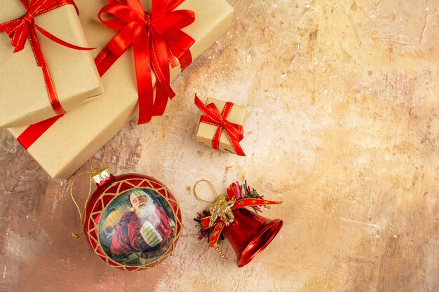 Bottom view xmas gifts in brown paper ribbon xmas tree toy on newspaper on dark background