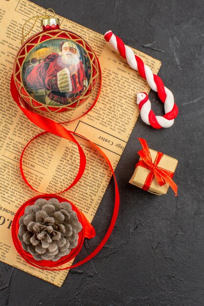 Bottom view xmas gifts in brown paper ribbon xmas tree toy on newspaper on dark background