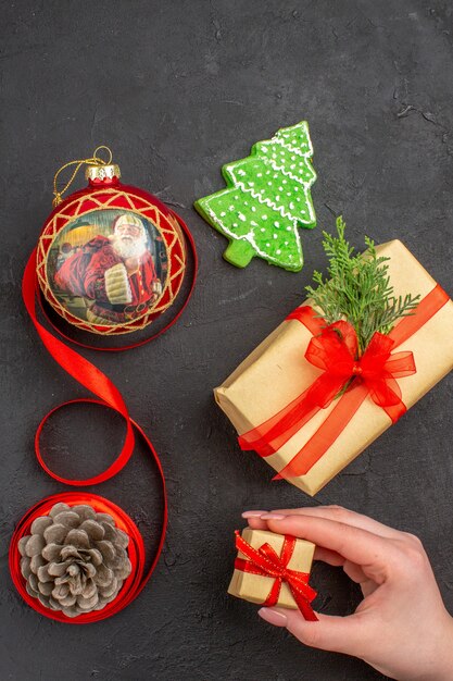 暗い上の新聞の茶色の紙のリボンのクリスマスツリーのおもちゃの底面図のクリスマスプレゼント