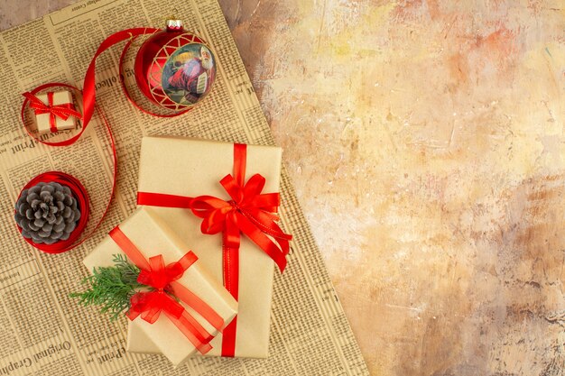 Bottom view xmas gifts in brown paper ribbon xmas tree toy on newspaper on dark