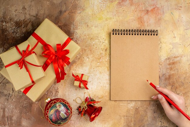 Bottom view xmas gifts in brown paper ribbon xmas tree toy on newspaper on dark