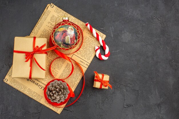 Bottom view xmas gifts in brown paper ribbon xmas tree toy on newspaper on dark