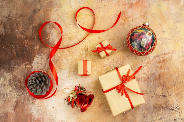 Bottom view xmas gifts in brown paper ribbon xmas tree toys on newspaper on beige background