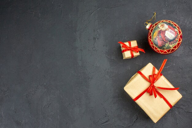 Рождественские подарки в коричневой бумажной ленте, рождественские елочные игрушки на газете на бежевом фоне, вид снизу