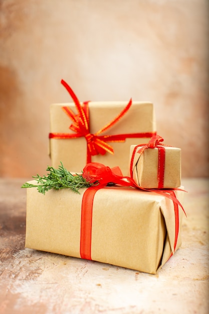 Рождественские подарки в коричневой бумажной ленте, рождественские елочные игрушки на газете на бежевом, вид снизу