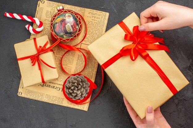 Бесплатное фото Рождественские подарки в коричневой бумажной ленте, рождественская елка, вид снизу, на газете на темноте