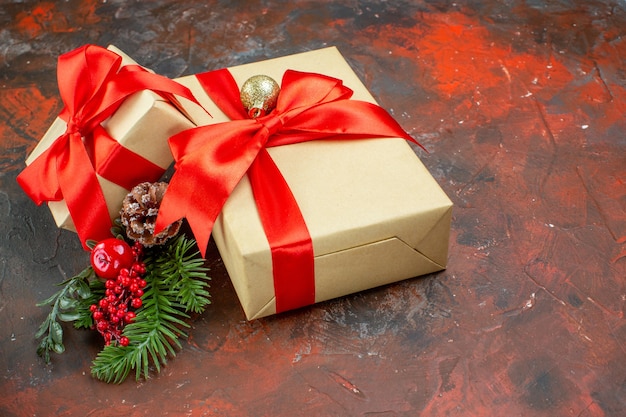 Free photo bottom view xmas gifts tied with red ribbon xmas tree branch on dark red table