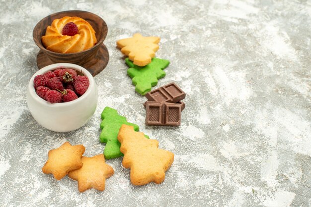 Bottom view xmas tree cookies bowl with raspberries on grey surface copy space