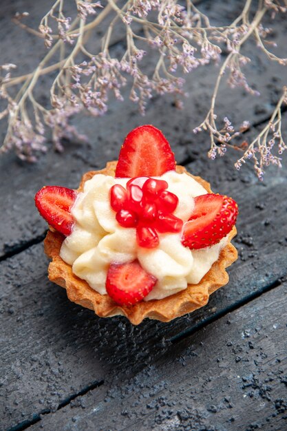 Botttom view tart with strawberry and pomegranate dried flower branch on dark background