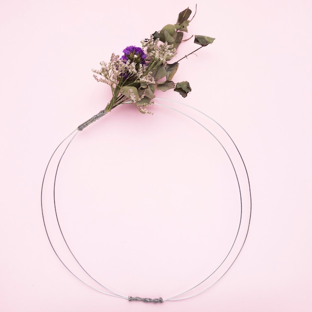 Bouquet of flower tied on metallic wire ring for frame on pink background