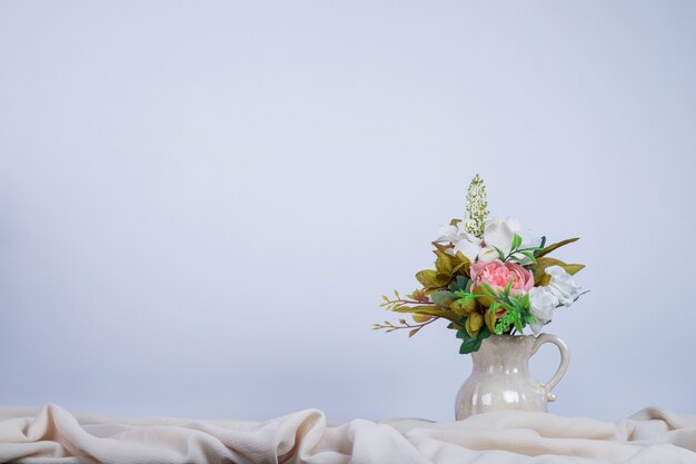 Bouquet of flowers in ceramic vase on dark wall.