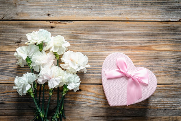 Free photo bouquet of flowers and heart shaped gift box on wooden background flat lay