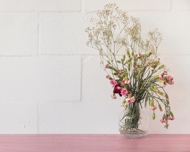 壁の近くの花瓶に花と植物の小枝の花束