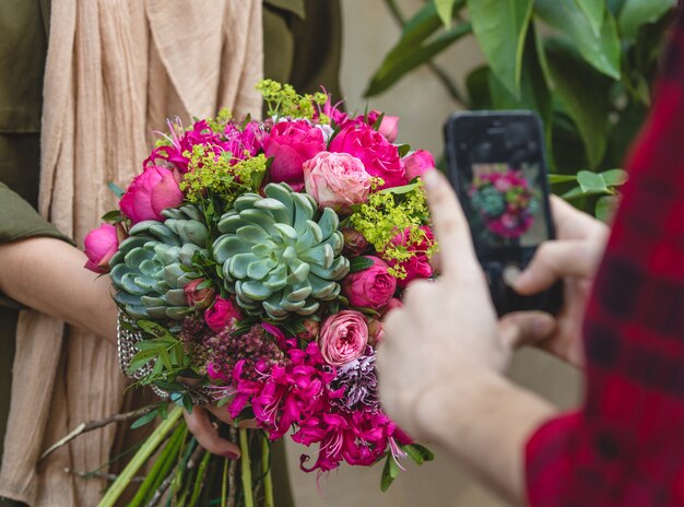 Bouquet of flowers and suculents in the hands of a women, mobile shooting from aside