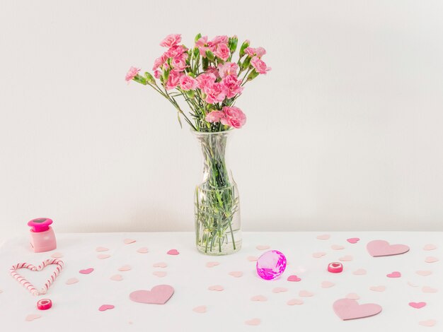 Bouquet of flowers in vase near set of paper hearts and candy canes 