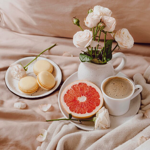 Bouquet of flowers with morning coffee and grapefruit on bed