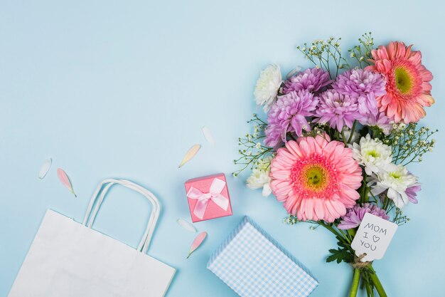 패킷, 선물 및 노트북 근처 태그에 제목을 가진 신선한 꽃의 꽃다발
