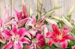 Free photo a bouquet of fresh lilies on a wooden surface. flower delivery concept.