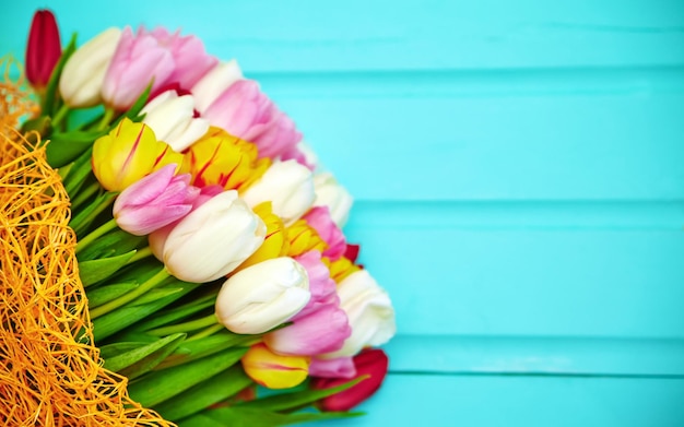 Bouquet of fresh multicolor tulip flowers on old blue wooden table