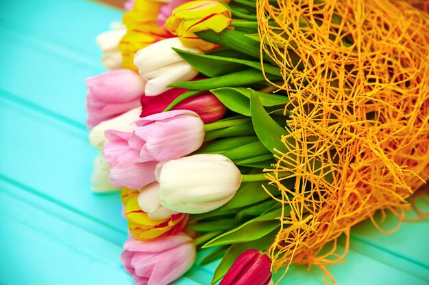 Букет свежих многоцветных цветов тюльпана на старом голубом деревянном столе