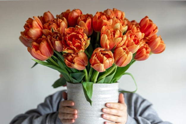 女性の手のクローズ アップで新鮮なオレンジ色のチューリップの花束