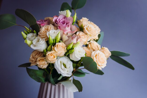 Bouquet of greenery and white roses put in a porcelain vase