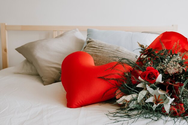 Bouquet and heart cushion on bed