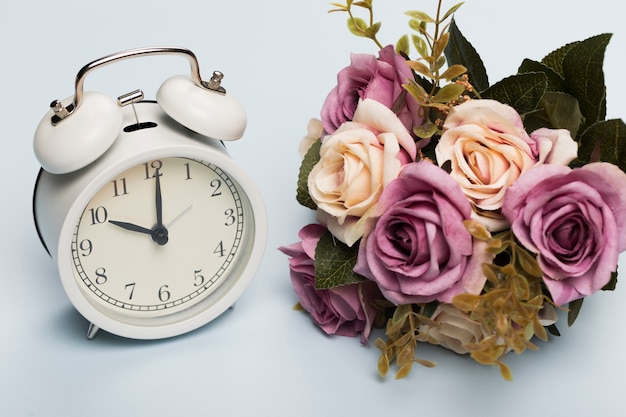 時計の横にあるバラの花束