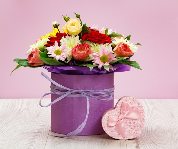 나무 판자에 야생화 꽃다발과 분홍색 선물 상자