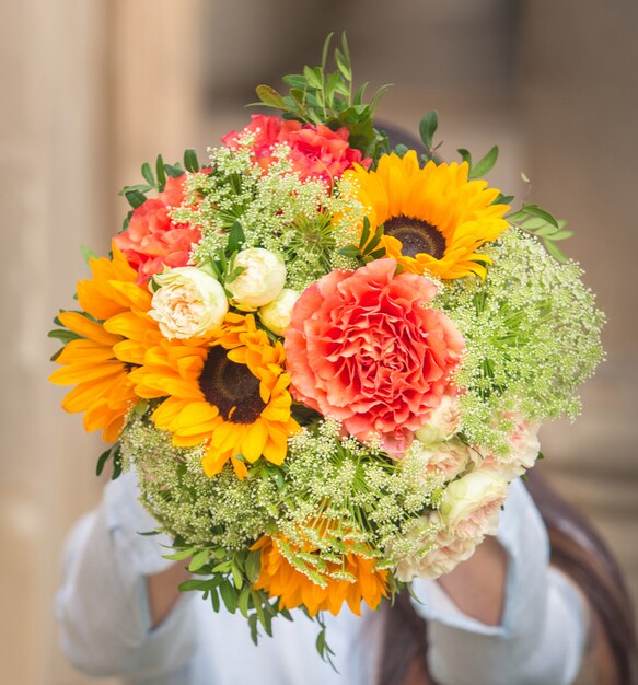 A bouquet of pink flowers and yellow sunflowers with green leaves  