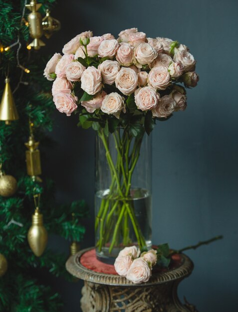 A bouquet of pink roses and a single branch of rose with green leaves inside a vase 