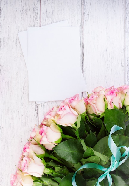 Bouquet di rose rosa con nastro blu su sfondo d'epoca in legno con documenti