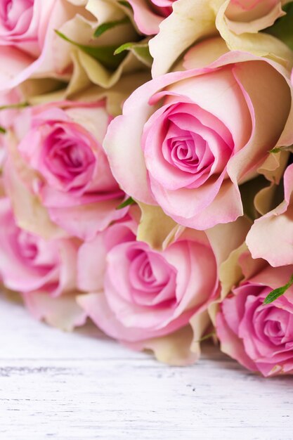 Bouquet of pink roses with blue ribbon on a vintage wooden background