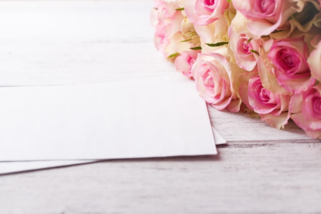 Bouquet of pink roses with blue ribbon on a vintage wooden background