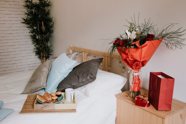 Bouquet and presents near bed with breakfast