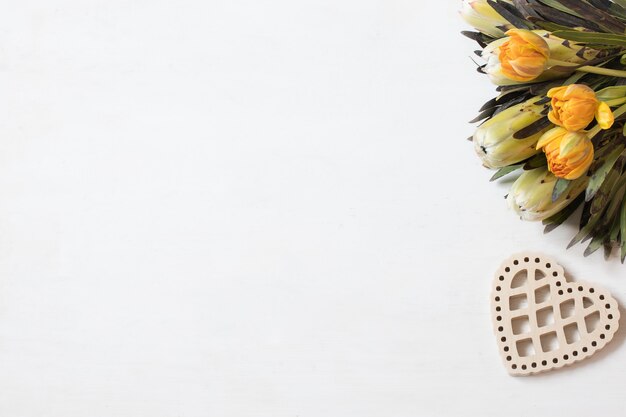 木製の装飾要素の上面図とプロテアの花とチューリップの花束。バレンタインデーのギフトのコンセプト。